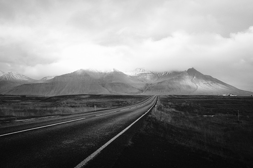 A long across the desert with cloudy hills in the distance shot in black and white