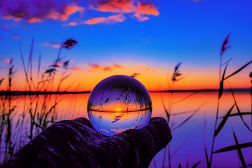 A beautiful selective focus shot of a crystal ball reflecting the breathtaking sunset with unique colors