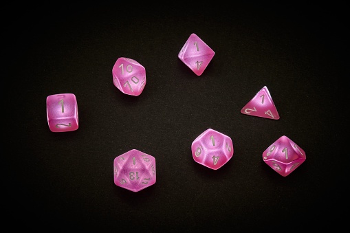 7 pink polyhedral dice used for table top role playing games
