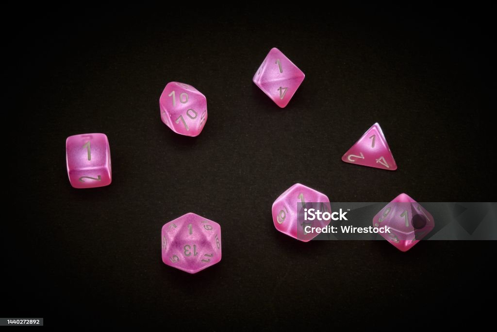 A standard set of 7 dice in pink for rpg games 7 pink polyhedral dice used for table top role playing games Dice Stock Photo