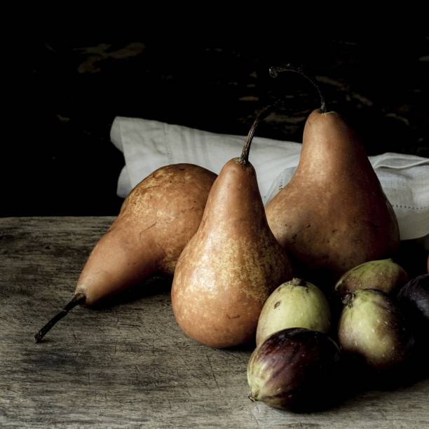 黒い背景を持つ木製の机の上の梨とイチジクの静物写真 - russet pears ストックフォトと画像