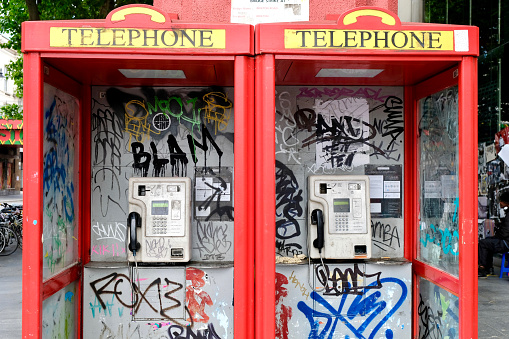 London. UK.  July 7th 2021.  Telephones covered with graffiti in the street outside Brixton tube station see little use and are now largely neglected by the mobile phone carrying public.
