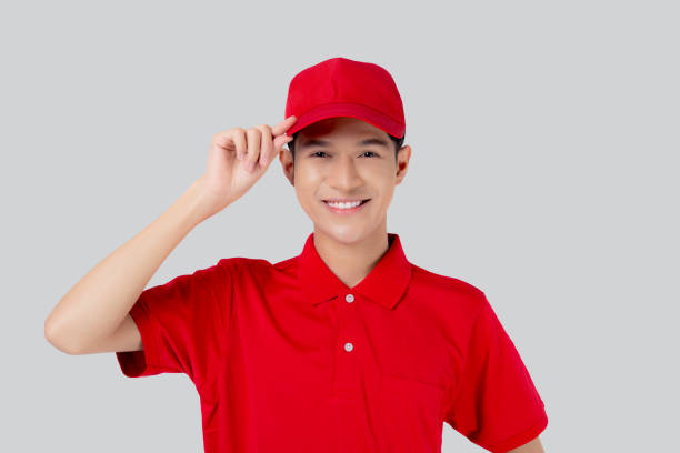 istock Young asian man in uniform and red cap standing and catch a hat with confident isolated white background, employee and shipping, courier and delivery, deliveryman and expression, logistic and cargo. 1440274856