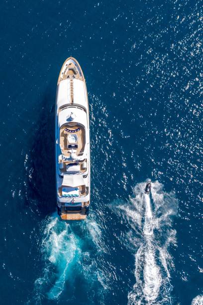 vertical high angle shot of a private yacht and a small motorboat sailing in the ocean - recreational boat small nautical vessel sea imagens e fotografias de stock