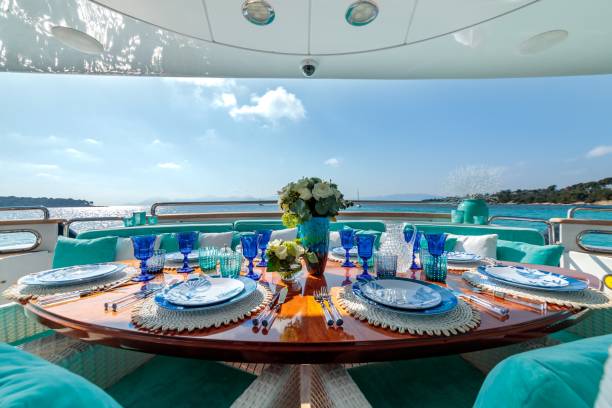 сервировка стола в океанской тематике с синими тарелками, бокалами для вина и букетом цветов на роскошной яхте - cruise ship cruise beach tropical climate стоковые фото и изображения