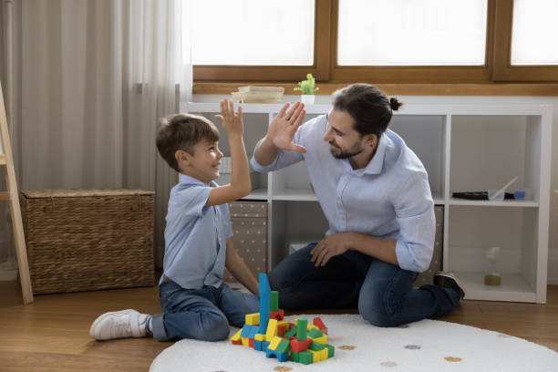 istock Father praises, gives high five to son while play cubes 1440276444