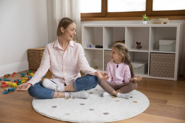 junge mutter lehrt kleine tochter meditationspraxis - yoga good posture women little girls stock-fotos und bilder