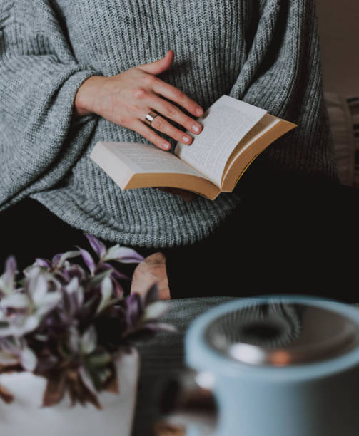 istock Female in a warm pullover leafing through a book, winter is the best season for reading 1440276605