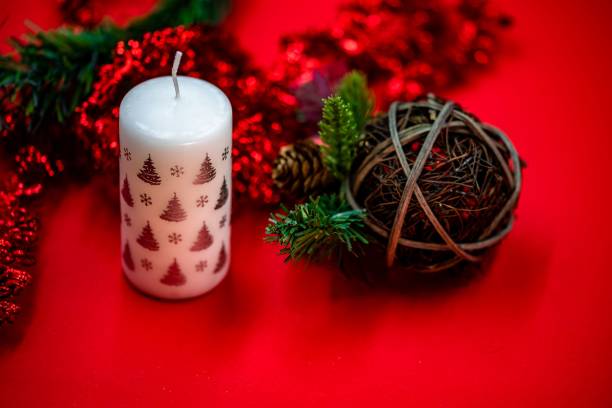 istock White candle alongside Christmas ornaments isolated on a red background 1440276729
