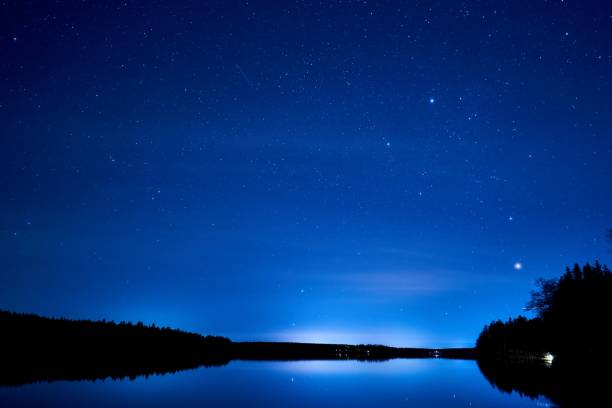 istock Mesmerizing starry night sky over a pond reflecting on the water surface 1440276855