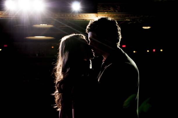 Male and a female kissing each other while standing on the stage in the theatre A male and a female kissing each other while standing on the stage in the theatre spark singer stock pictures, royalty-free photos & images