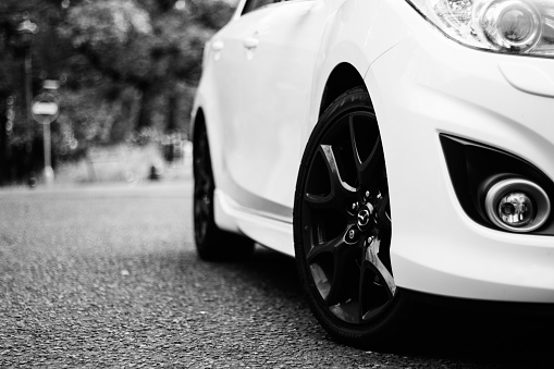 Wolverhampton, United Kingdom – May 06, 2016: A grayscale low angle shot of a white Mazda driving in the street of Wolverhampton  city in the UK