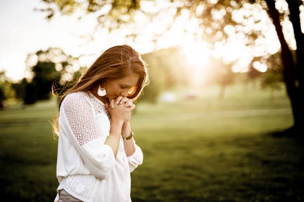 Closeup shot of a female praying with a blurred background A closeup shot of a female praying with a blurred background church ladies stock pictures, royalty-free photos & images