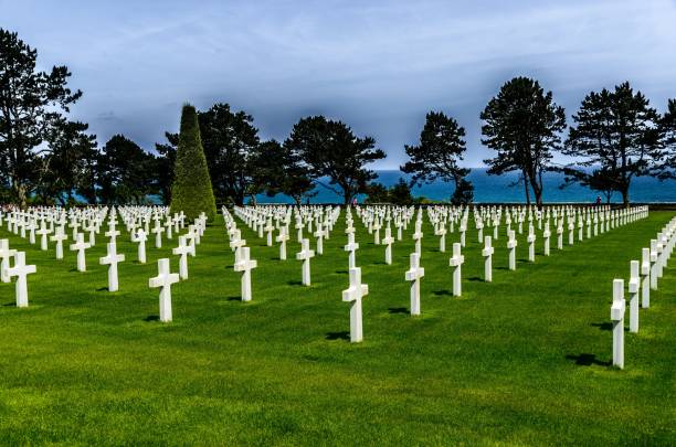 istock Cemetery with white stone crosses surrounded by green trees under the cloudy sky 1440279440