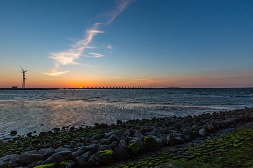 A beautiful shot of a storm surge barrier and windmills in Zeeland province in the Netherlands on sunset