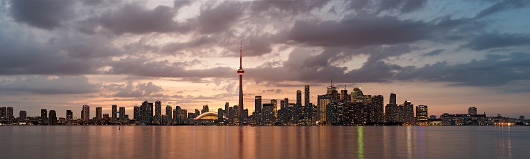 A panoramic shot of the Toronto city in Canada with illuminated buildings during sunset
