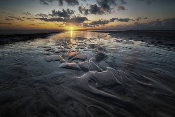 istock Beautiful scenery of the sunset reflected in a mudflat under the cloudy sky 1440282283