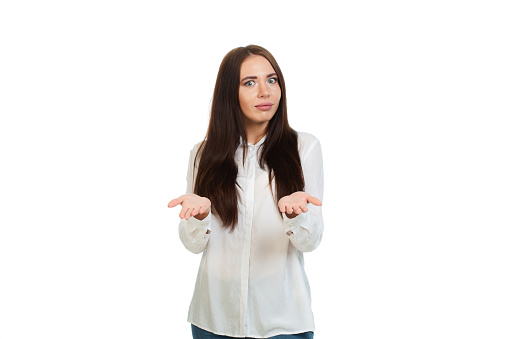 Young, beautiful girl in a whhte shirt on a white background. Gesture of offer. Isolated.