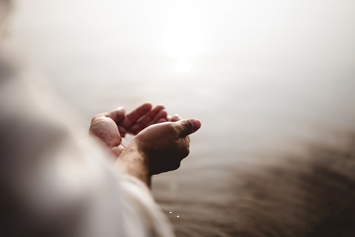 Toma de ángulo alto de Jesucristo sosteniendo agua con sus palmas photo