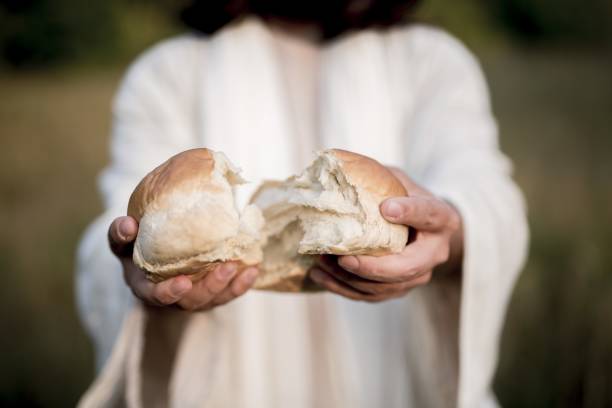 nahaufnahme von jesus christus, der das brot spaltet, mit verschwommenem hintergrund - communion table stock-fotos und bilder