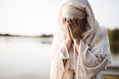 istock Closeup shot of a female wearing a biblical robe crying  - concept confessing sins 1440284840