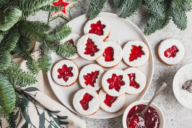 Linzer cookies with jam in a white plate on a white background. Traditional Christmas homemade Austrian sweet dessert food.