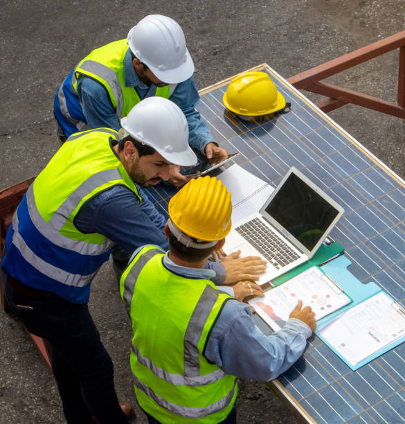 brainstorming communications of technician professional team  in safety helmets and uniforms with solar photovoltaic panels - solar power station solar panel energy electrician imagens e fotografias de stock