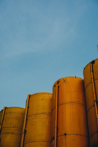 A vertical shot of four yellow metallic silos with the blue sky in the background