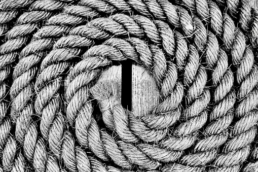 A closeup shot of rope on a wooden surface in black and white