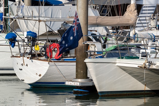 The Australian flag flying from the bow of a yacht in a marina