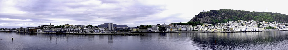 A beautiful view of Alesund harbor, Norway, with a clear lake and a lot of buildings on the shore