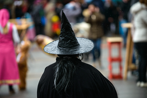 A back view of a woman in a witch hat at the costume carnival