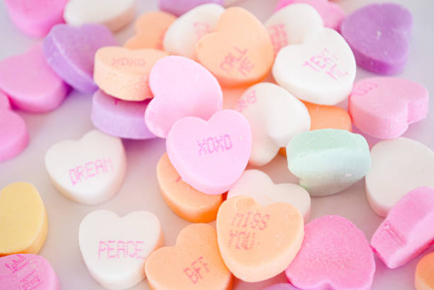 closeup of the colorful heart-shaped candies with different romantic texts on them - lots of candy hearts imagens e fotografias de stock