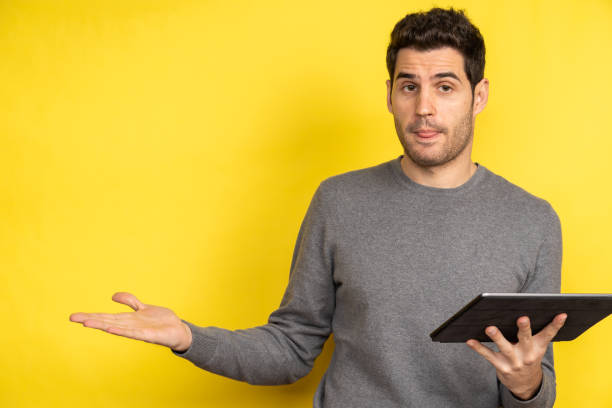 istock Handsome Caucasian man holding a laptop and working on a yellow background 1440292210