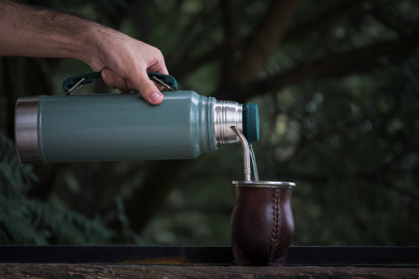 Selective Focus Shot Of A Hand Pouring Water From A Thermos In Calabash Mate  Cup With Straw Stock Photo - Download Image Now - iStock