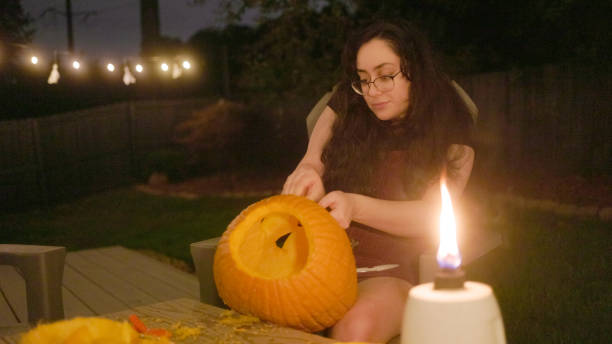 istock Woman Carving Pumpkin - Jack O’Lantern - Halloween - Back Yard - String Lights 1440293596