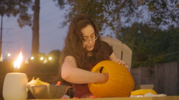 istock Woman Carving Pumpkin - Jack O’Lantern - Halloween - Back Yard - String Lights 1440293634