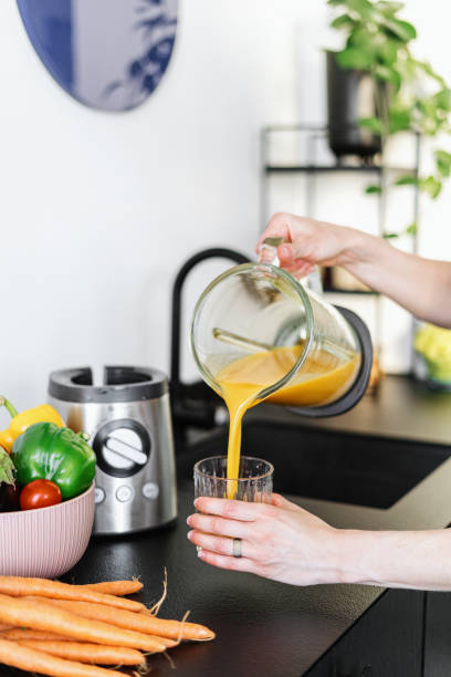 istock woman making fresh juice with carrot at kitchen 1440293836