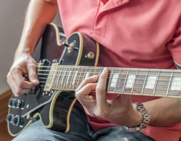 istock Man playing guitar at home 1440294613