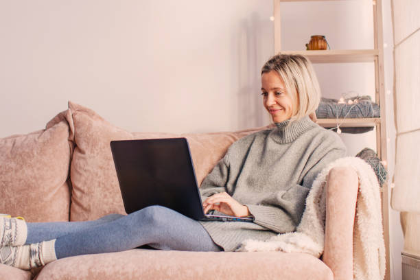istock Happy middle aged woman using her laptop on the sofa at home 1440298203