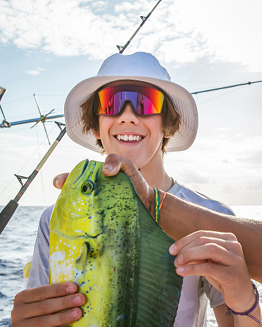 Teenage boy in white bucket hat with colorful sunglasses with green and yellow fish
