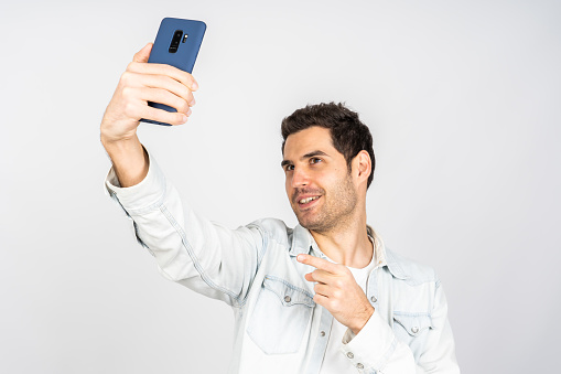 A handsome Caucasian man holding a phone and doing a selfie