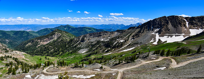 A panoramic mountain scene of the Wasatch Mountains from the top of Snowbird in summer.
