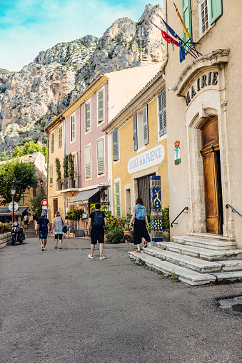 Tourists walking past the Town Hall at the village of Moustiers Sainte Marie in the Provence region of France.
