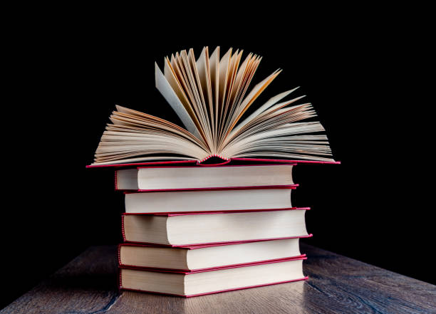 istock Stack of red-bound paper books on a wooden table. 1440309085