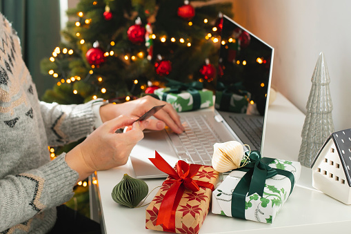 Female hand holding card. Woman using laptop. Christmas online shopping concept. Winter holidays sales.