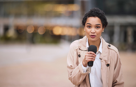 Black woman, news and reporter, microphone and journalist talking, information and journalism in urban portrait. Young, African American and broadcast, reporting and press, media and professional.