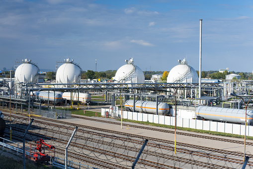 Concept for non-renewable technology and fossil fuels large gas and oil refinery with tanks and pipelines next to loading dock with railroad tracks