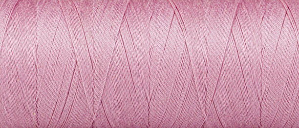 istock Texture of threads in a spool of pink color on a white background 1440317228