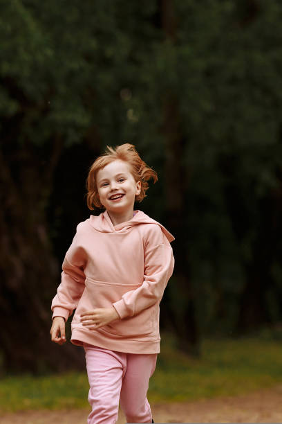 A girl in pink runs through the park